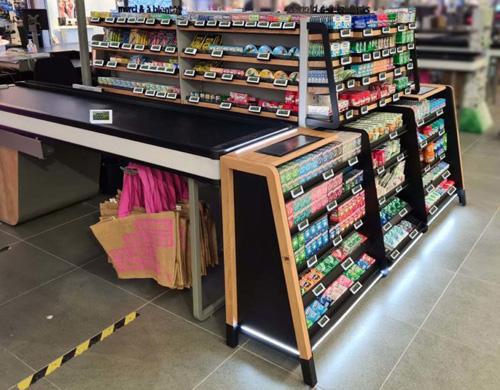Customer selecting an impulse product from a checkout display while waiting to pay in a retail store.