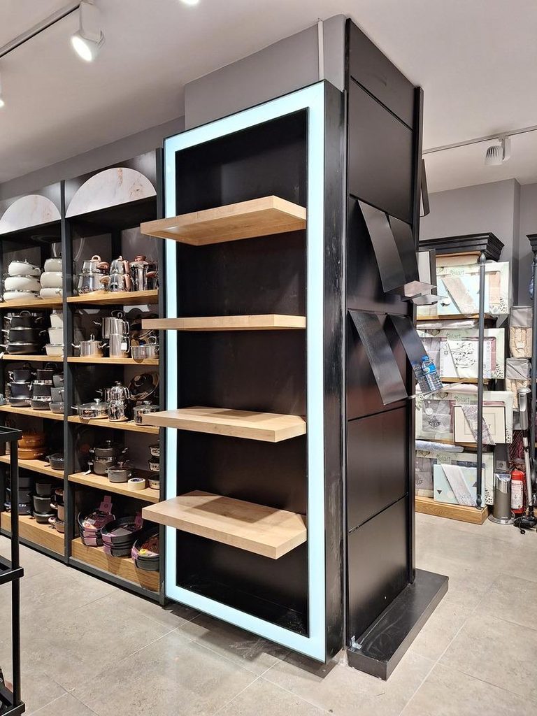 Modern freestanding retail display with wooden shelves, black metal frame and integrated LED lighting designed for premium retail environments.